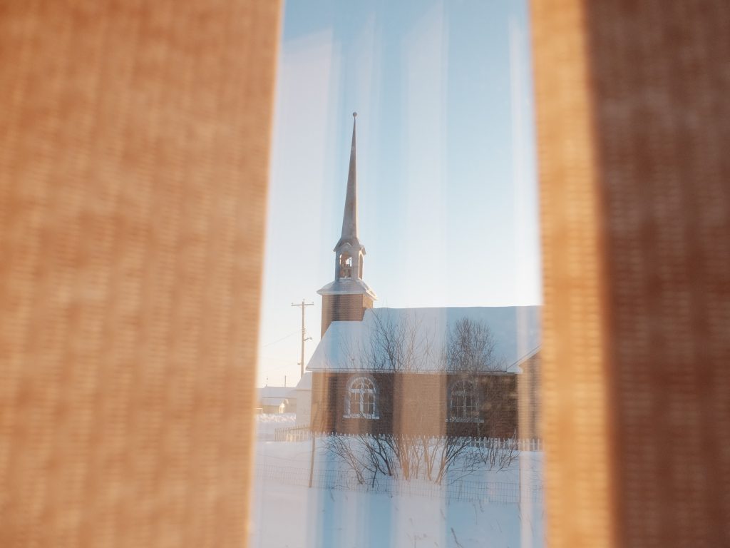 Image of a church in the remote town of Lac Brochet in northern Manitoba. Winnipeg Wedding Photographer Michael Scorr captured this through the blinds of a window on a Fujifilm x30 and processed in camera with a Classic Kodak Chrome recipe.