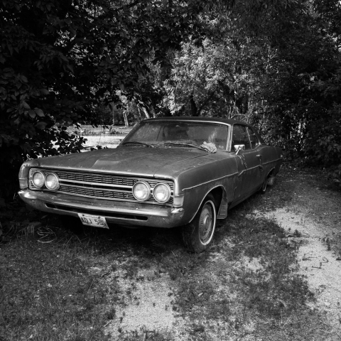 Black and white image of an old Ford car with a rag on the hood.