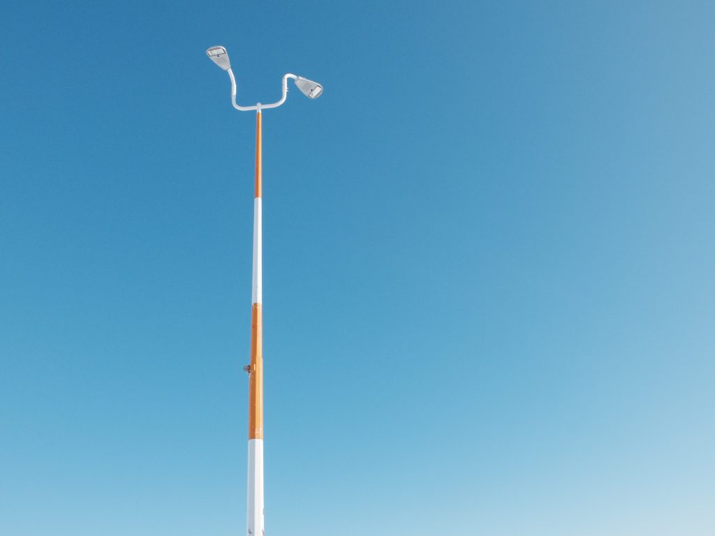Image of a lone light post against a bright blue sky.