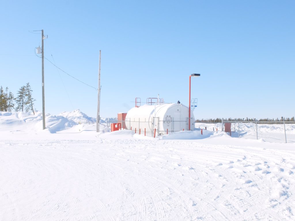 Image of an oil tank surrounded by snow with a bright blue sky.