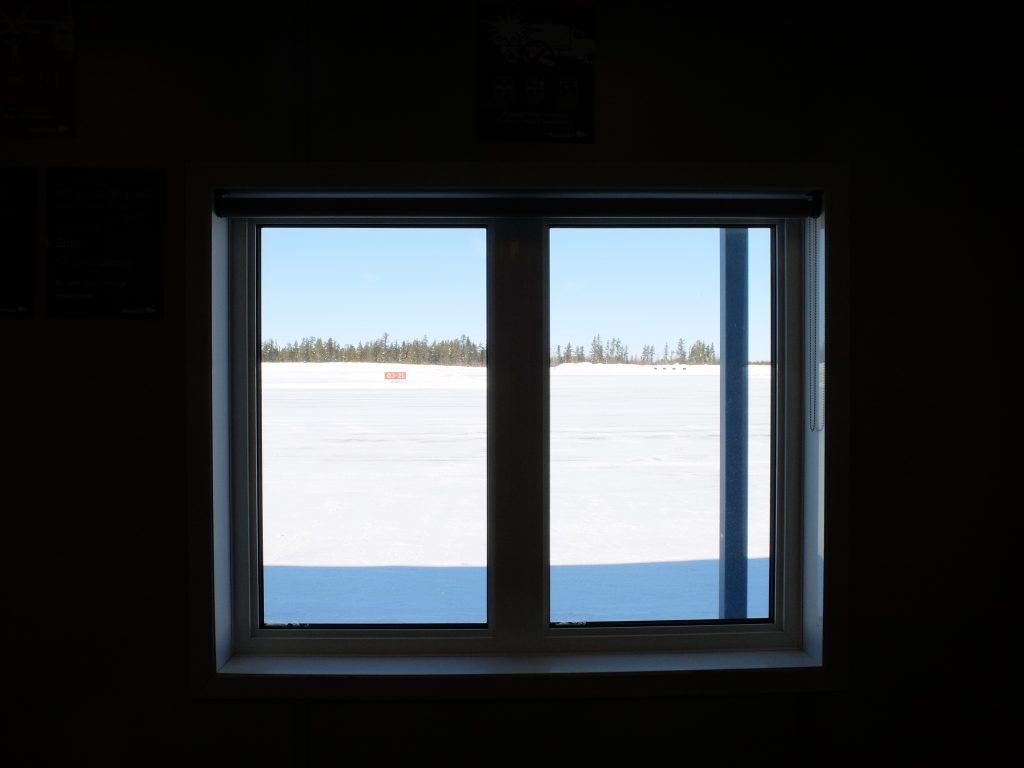 Picture of a window looking out onto an air strip in winter. 